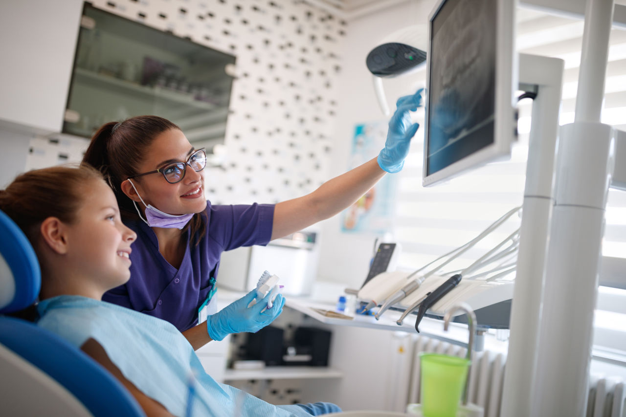 Dentist in dental ordination with female young patient looking at her dental x-ray 