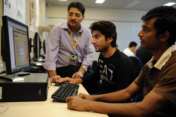 An IT teacher watching students research on a computer