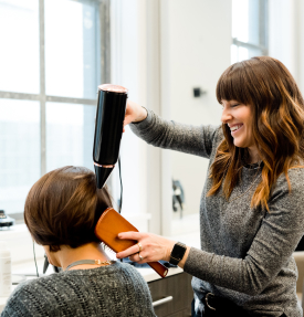 Hairdresser blow drying client's hair