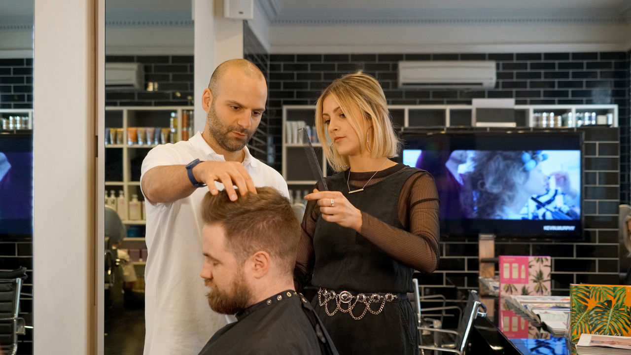 Female student with male teacher in hairdressing salon