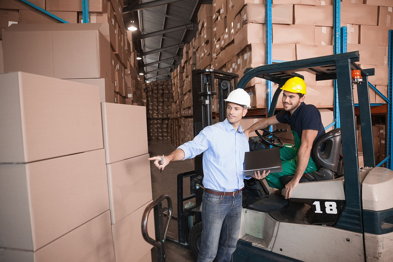 Warehouse manager talking with forklift driver in warehouse