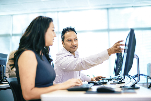 Workers discussing file on desktop computer