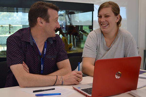 Two people sharing a laptop and having a discussion