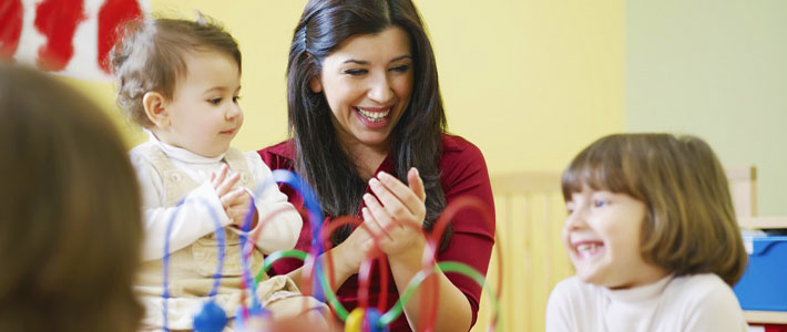 Laughing childcare teacher and children group 