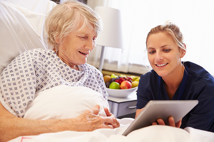 Nurse Talking To Senior Female Patient In Hospital Bed