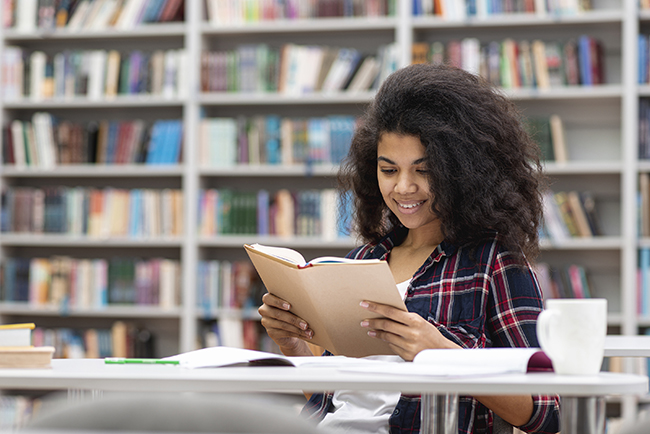 Lady reading book in library at table