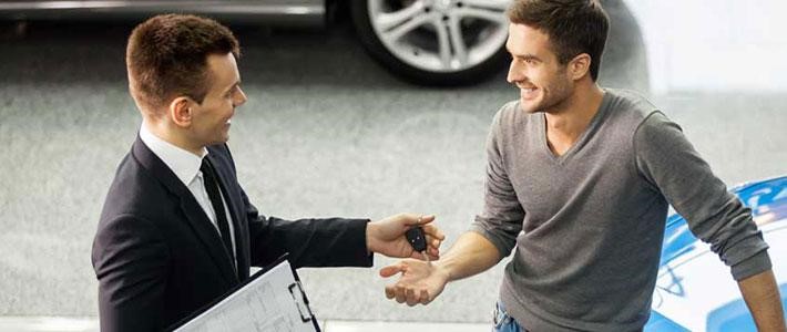 Car salesperson handing over key to customer