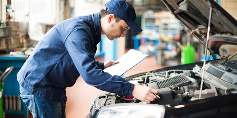 Automotive electrician inspecting components in car engine bay