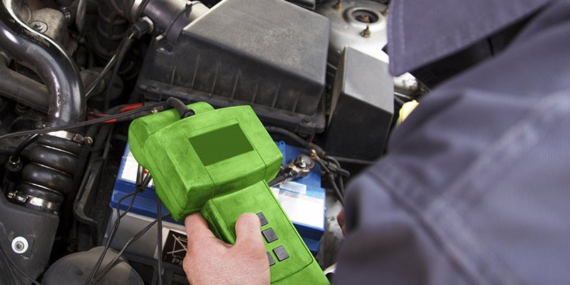 Automotive electrician testing components in engine bay