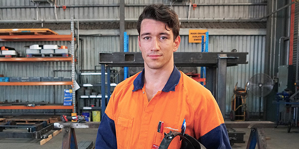 Young man in high vis shirt holding welding mask