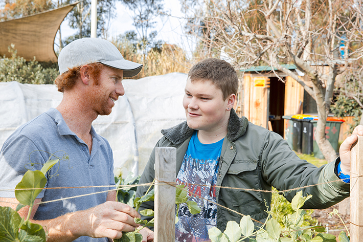 Two students talking while checking on a garden