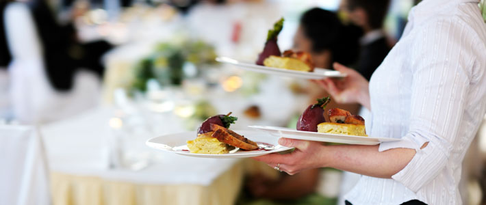 Close up of waiter carrying two plates out to a table