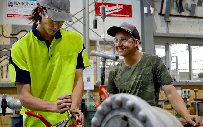 Two tradie students with protective eye wear on using tools 