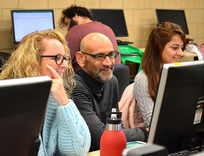 Three people looking at a computer and smiling