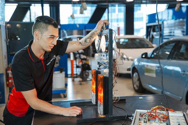 Image of male student testing brake lights on a car