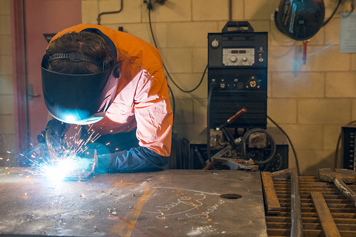 A person welding with a face shield on