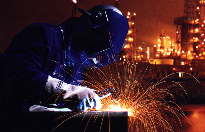 A person welding with a face shield on
