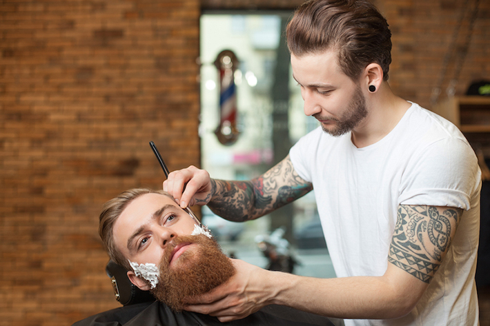 Male barber shaving a mans beard