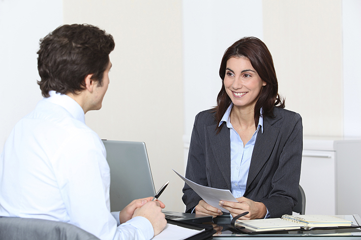 Woman sitting at desk facing a man