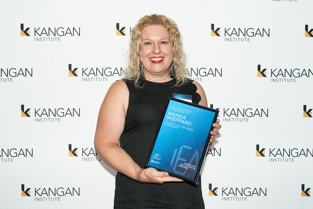 Student holding award and facing camera smiling